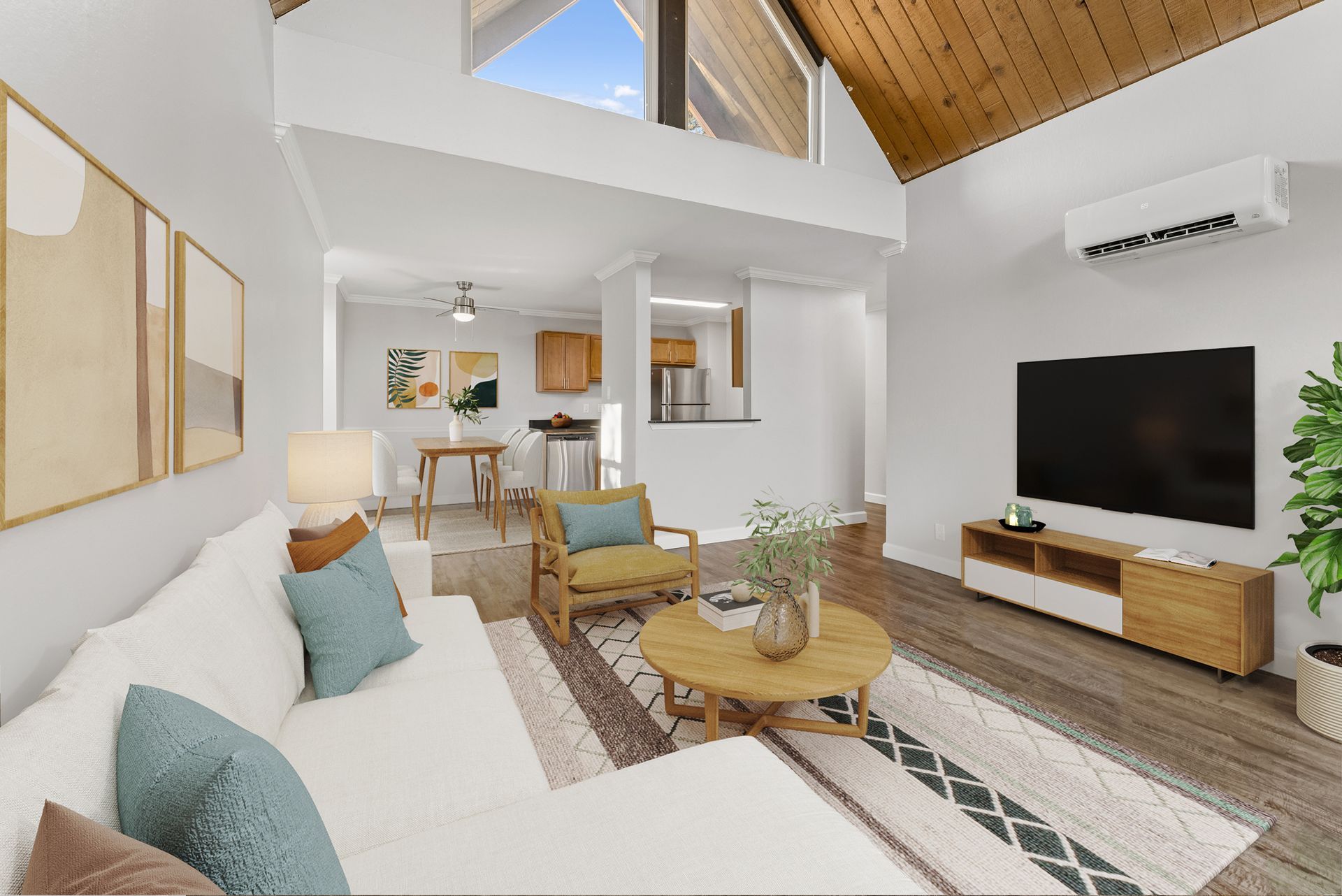 Bright modern living room with white sofa, TV, wood accents, and vaulted ceiling