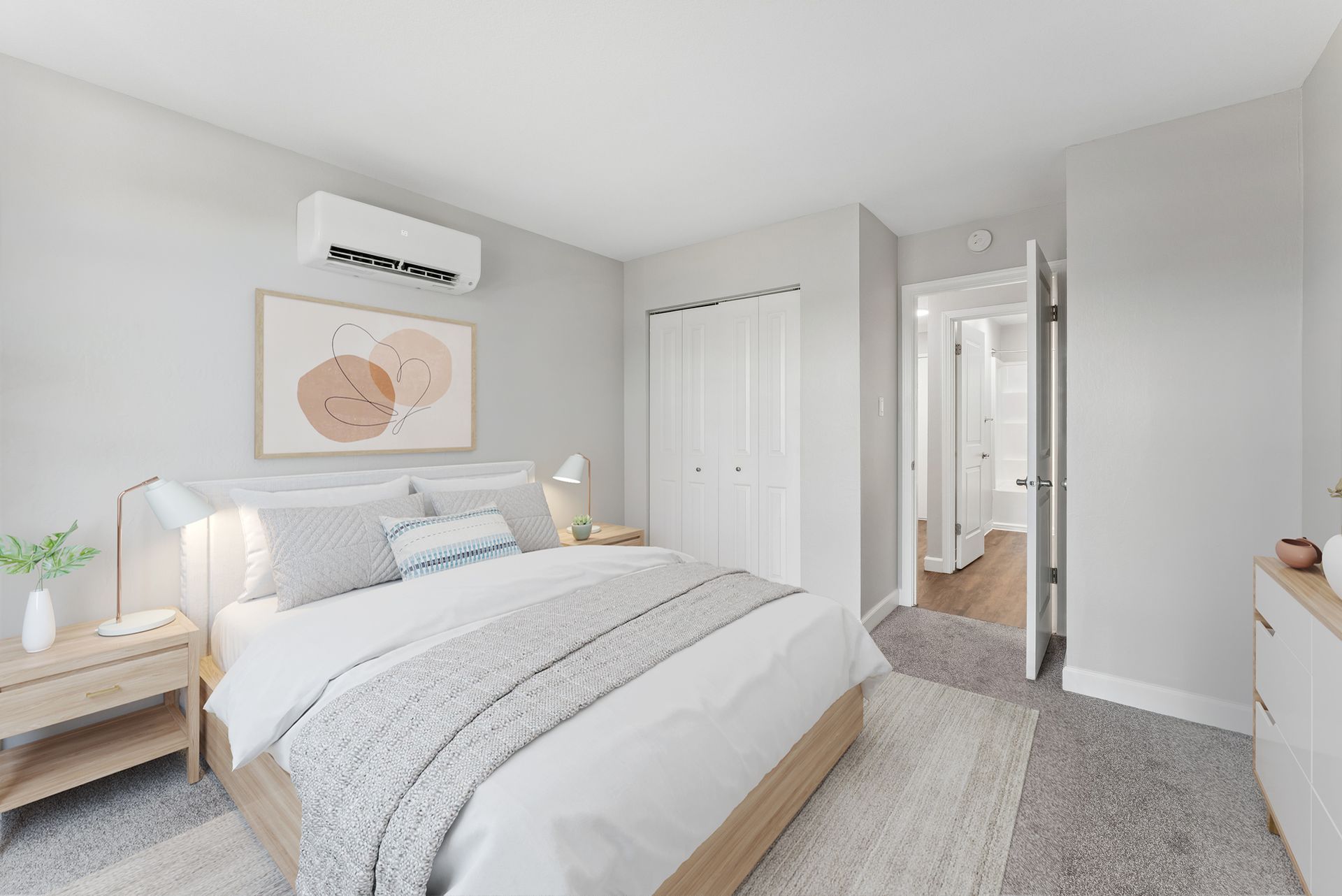 Bright bedroom with a neatly made bed, bedside lamp, wall art, and an adjoining hallway.