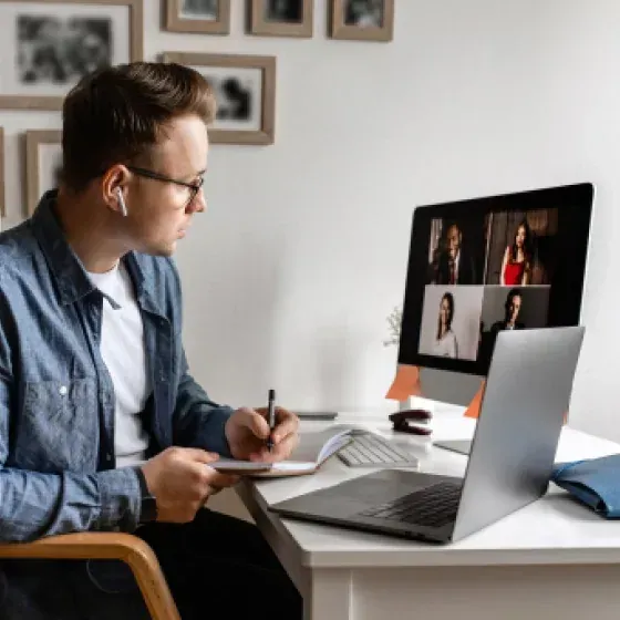 A man is sitting at a desk with a laptop and a computer.