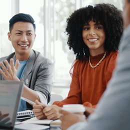 A group of people are sitting around a table with a laptop.