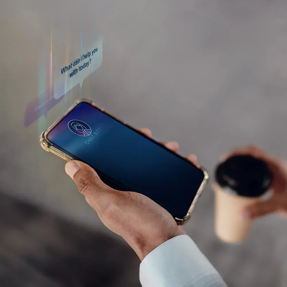 A person is holding a cell phone in their hand next to a cup of coffee.