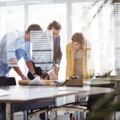 A group of people are standing around a table looking at a piece of paper.