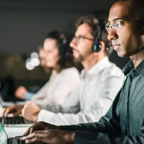 A man wearing a headset is typing on a laptop