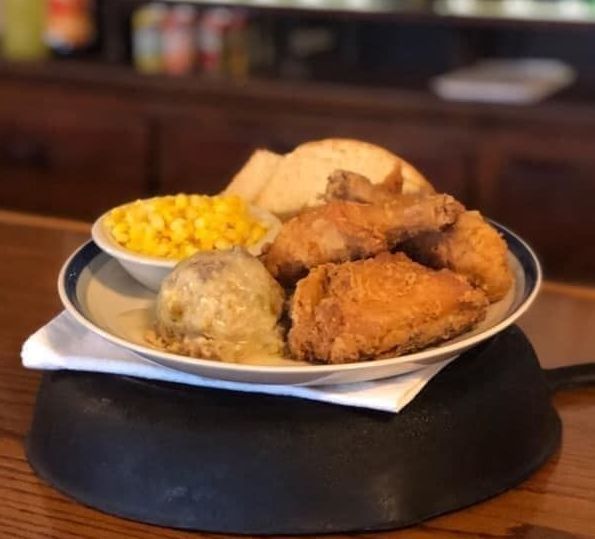 A plate of fried chicken mashed potatoes and corn on the cob