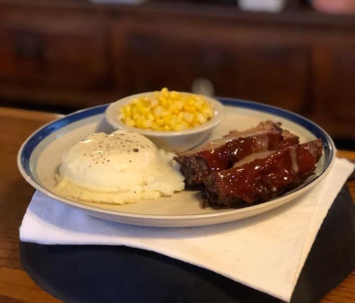 A plate of food with ribs mashed potatoes and corn on the cob