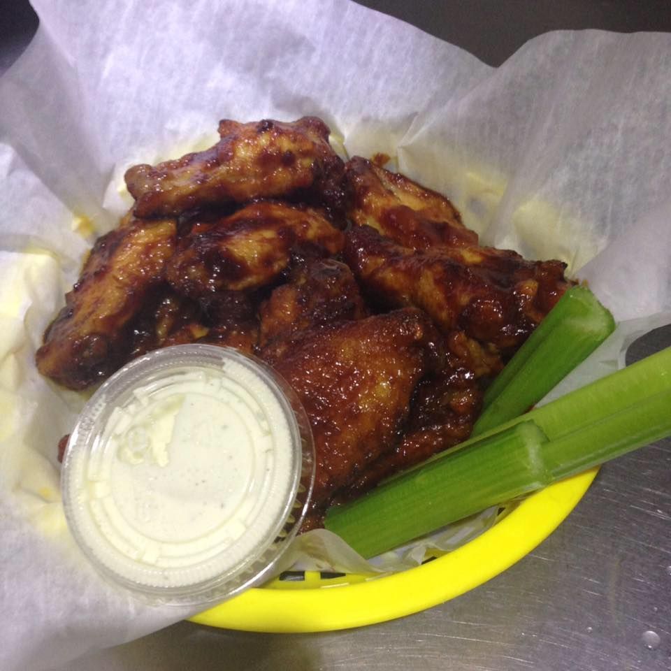 A yellow basket filled with chicken wings celery and ranch dressing
