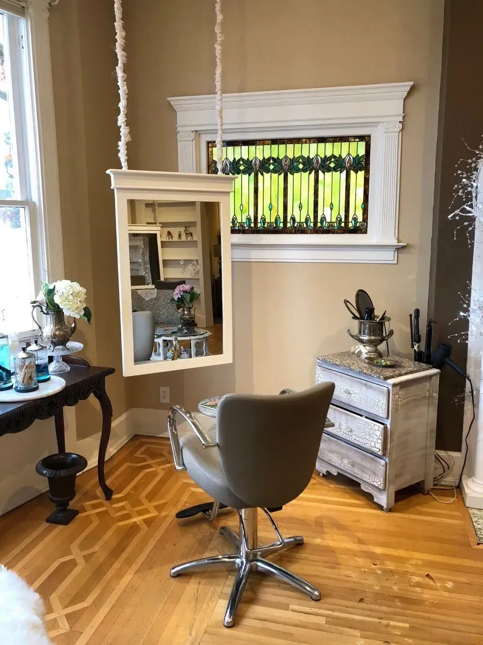 A hair salon with a chair and a mirror hanging from the ceiling.