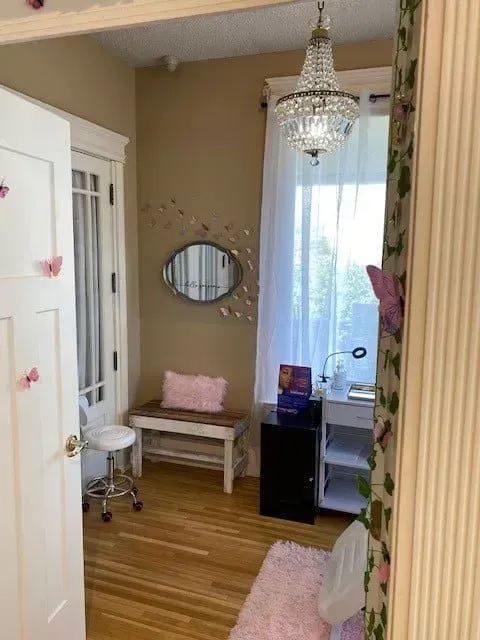A room with a bench, mirror, and chandelier.