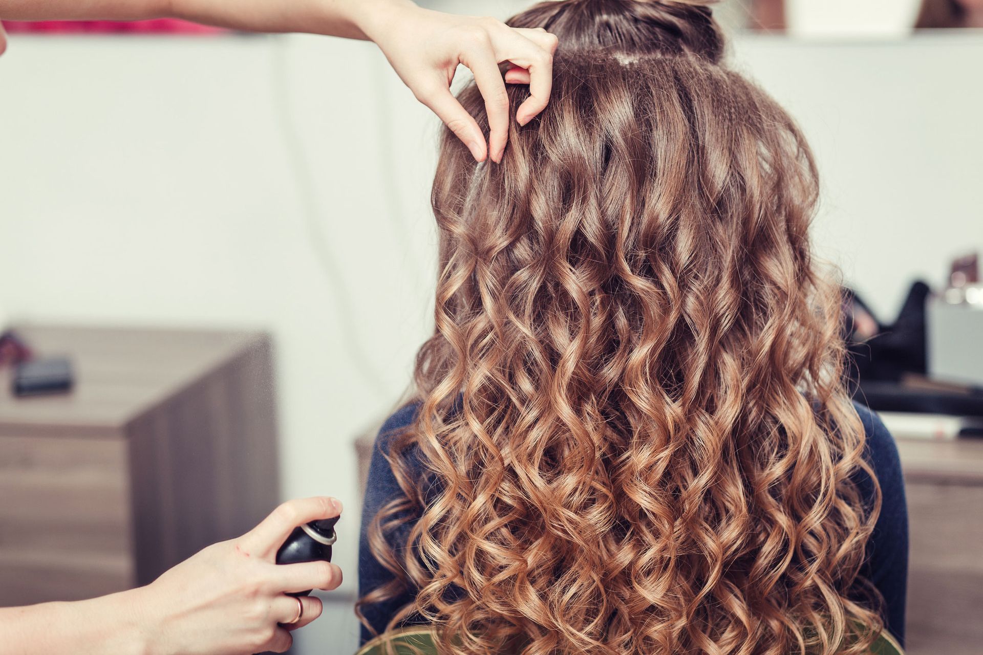 A woman is getting her hair done by a hairdresser in a salon.