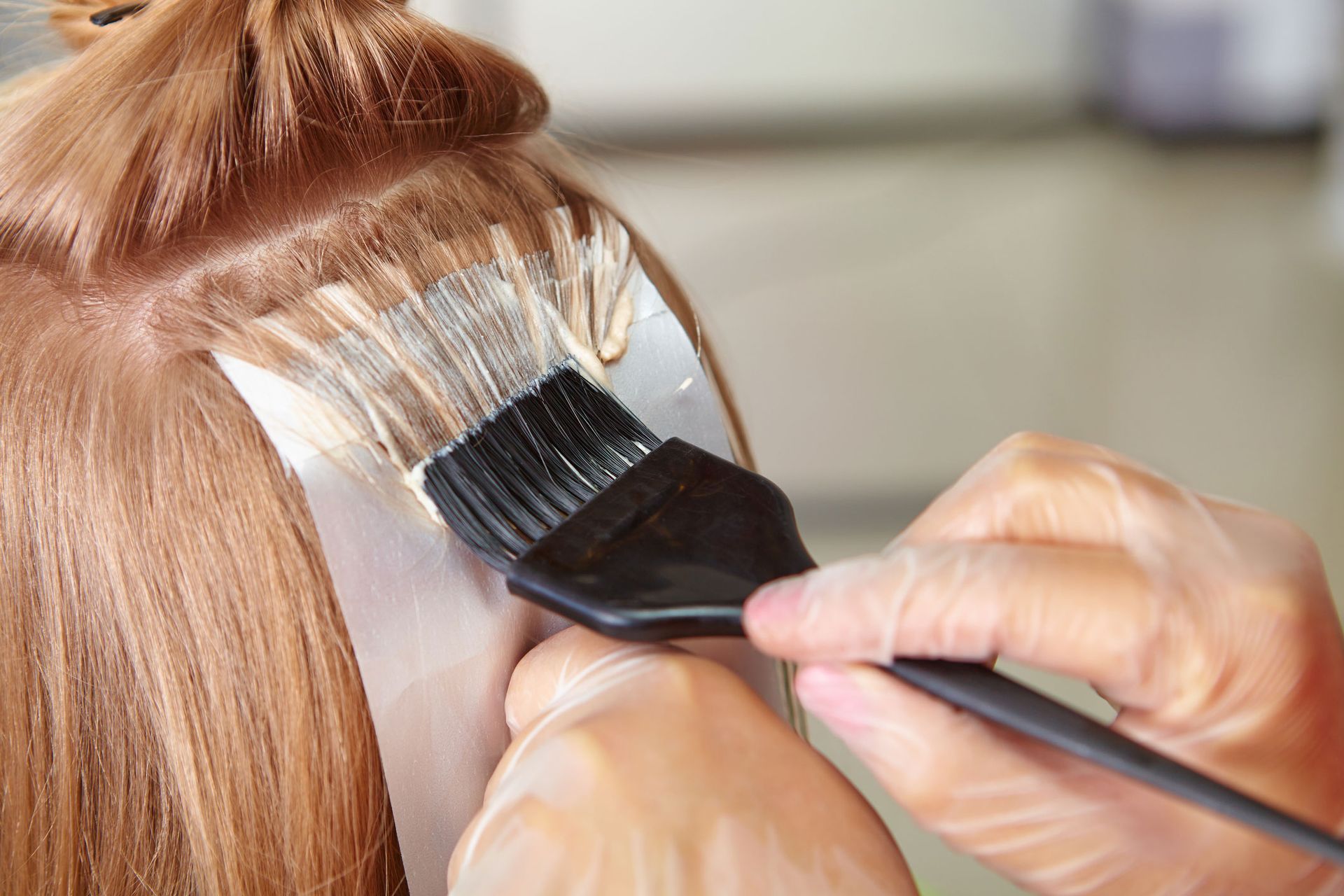 A woman is getting her hair dyed by a hairdresser.