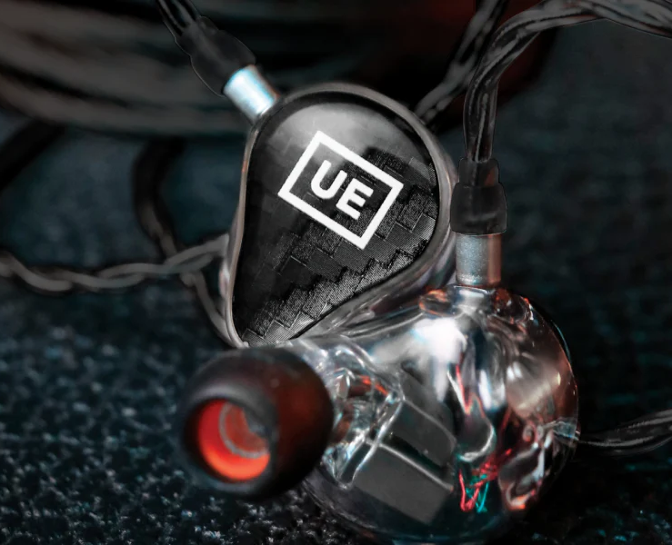Silver and black in-ear headphones. The left earbud displays the UE logo in white on a black background.