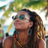 Woman with dreadlocks and sunglasses smiles outdoors.