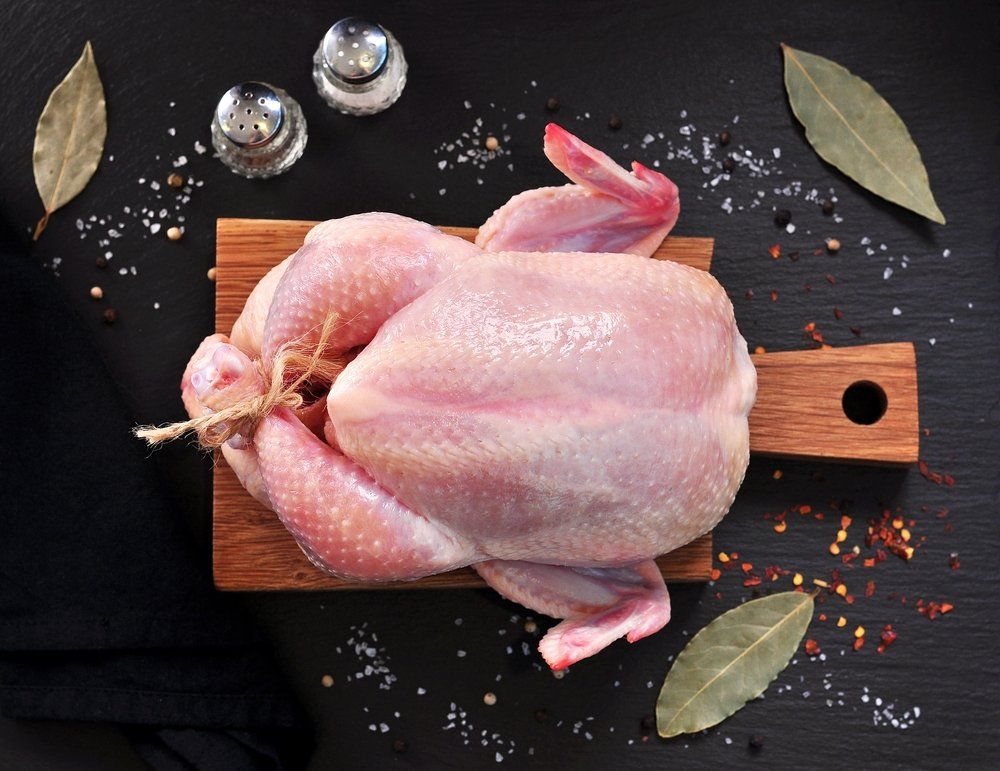Raw Chicken with Spices on a Wooden Board on a Black Stone — Byron Bay Pork & Meats Butchery in Mullumbimby, NSW