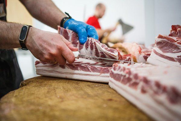 Butcher Carefully Chopping a Large Portion of Meat — Byron Bay Pork & Meats Butchery in Byron Bay, NSW