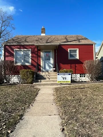 A red house with a for sale sign in front of it.