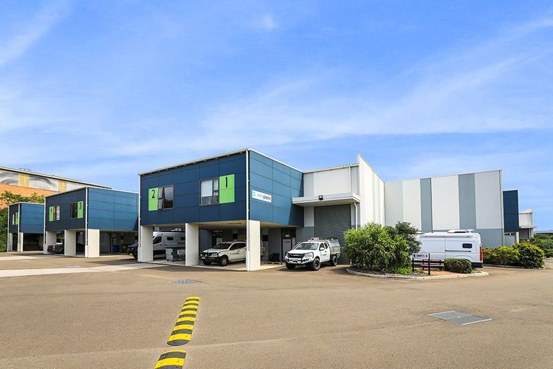 Commercial buildings with vehicles parked underneath, blue and white exterior, clear sky.