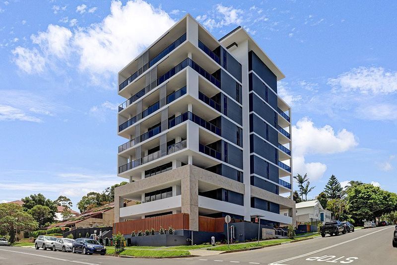 Modern apartment building with balconies on a sunny day with blue sky and clouds.
