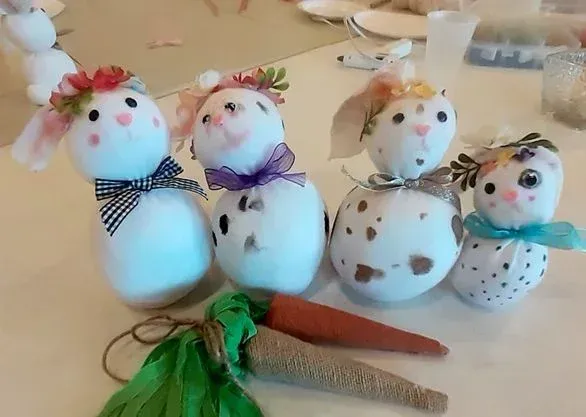 Four small handmade snowman figurines with scarves and hats on a table