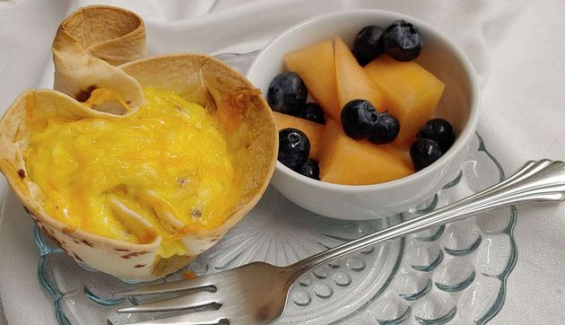 Dessert cups with mango chunks and blueberries, topped with whipped cream on a glass plate