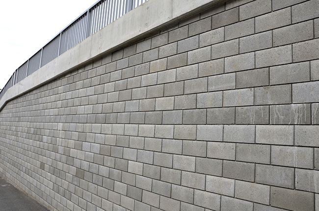 A large brick wall with a bridge in the background