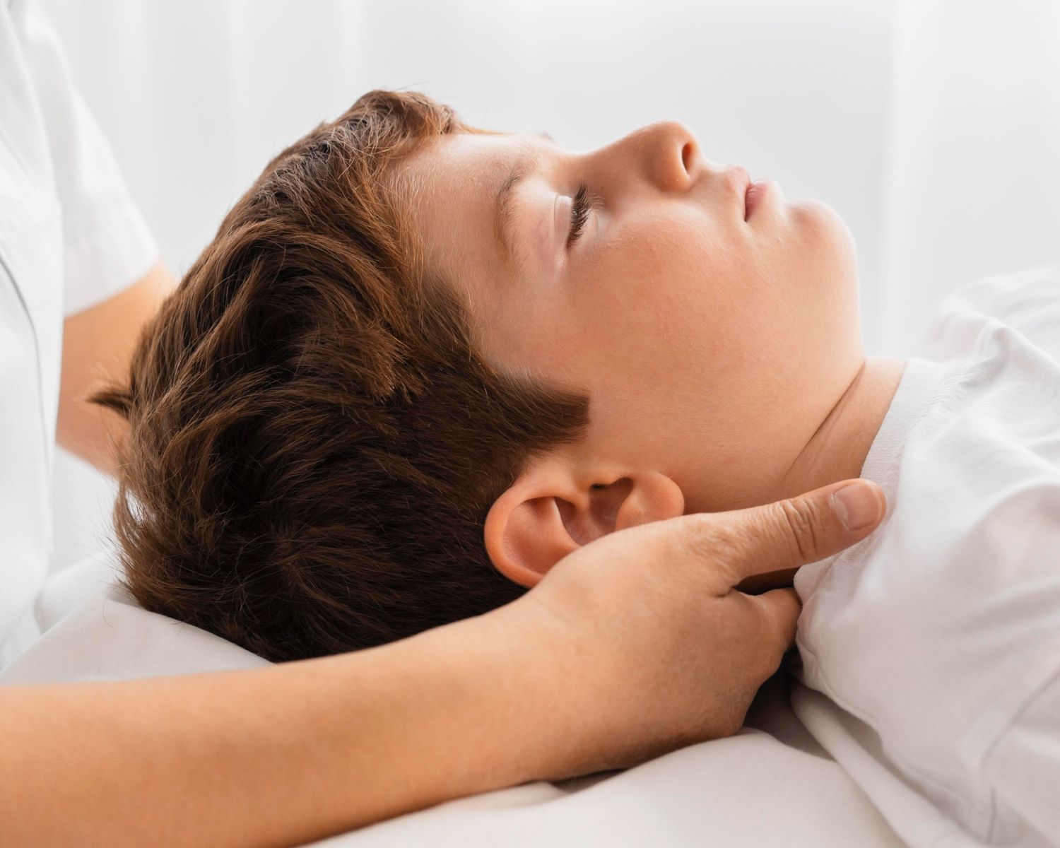 Young person lying on a bed while a hand gently checks their neck pulse