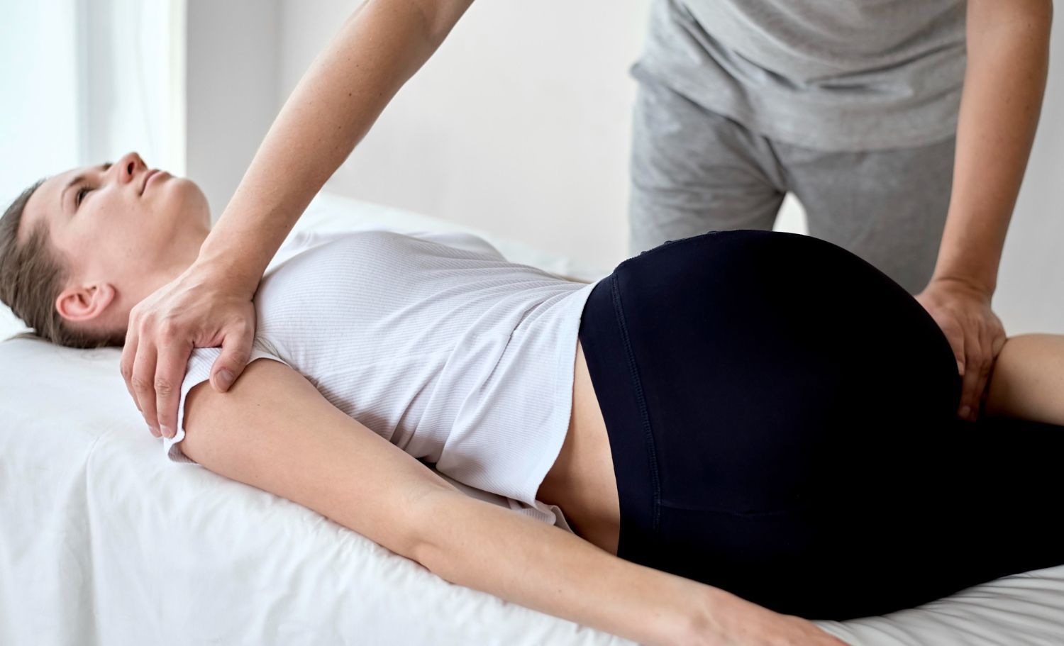 Physical therapist stretching a person’s shoulder while they lie on a treatment table