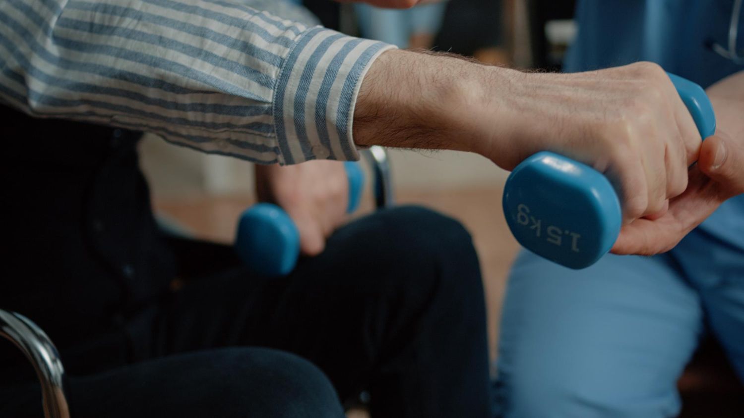 Person holding a blue dumbbell during an exercise session indoors