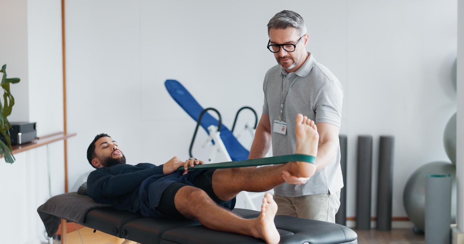 Physical therapist assisting a patient stretching on a treatment table in a clinic.