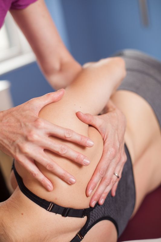 Hands performing a back massage on a person lying on a table.
