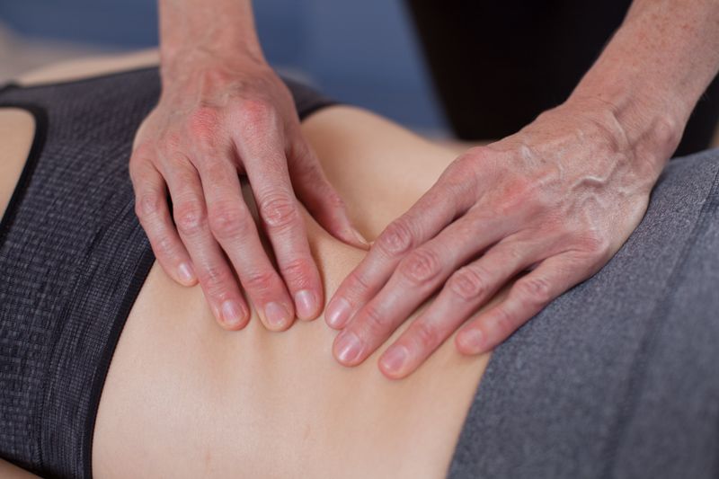 Hands performing a back massage on a person lying on a table.