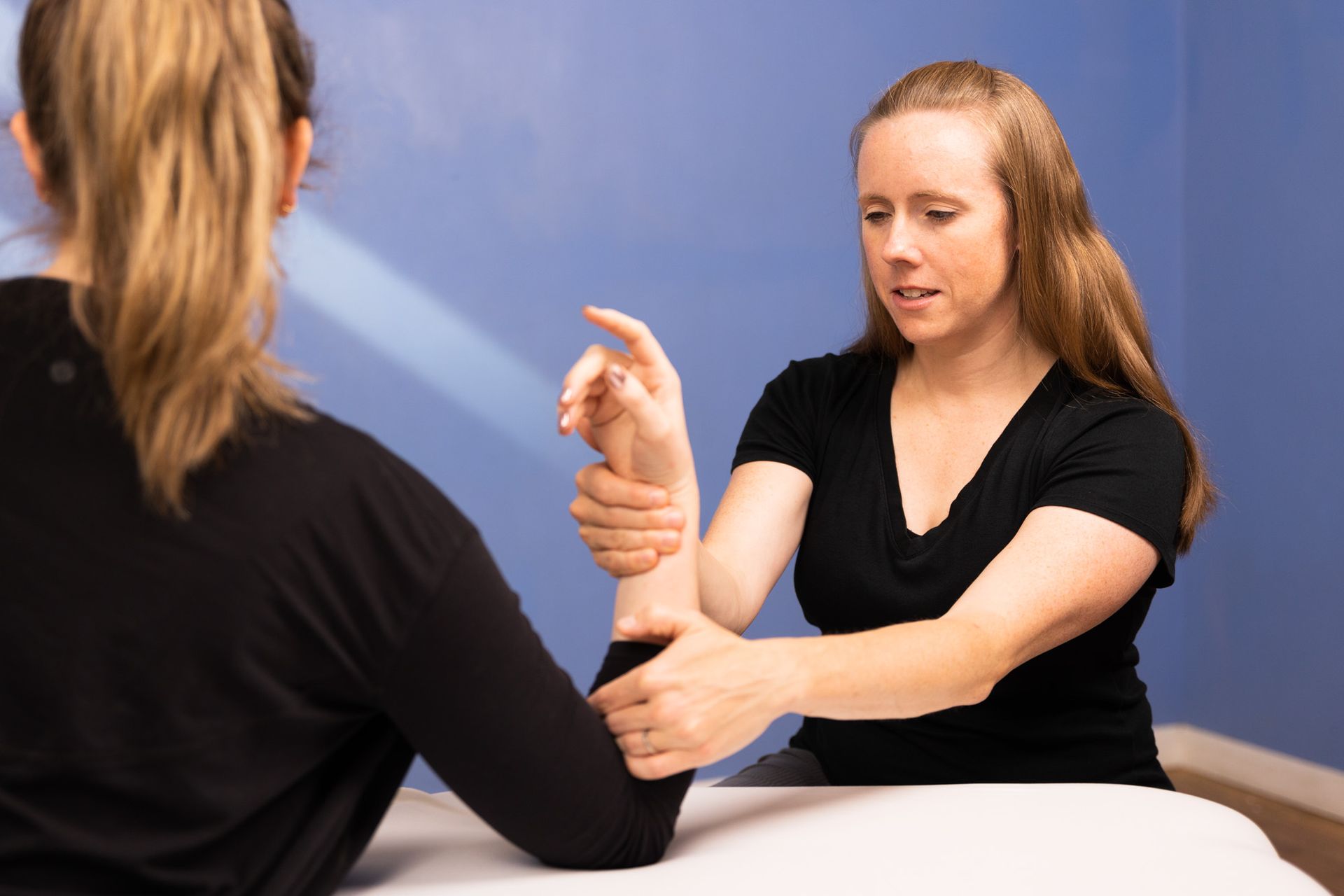 Person holding a blue dumbbell during an exercise session indoors