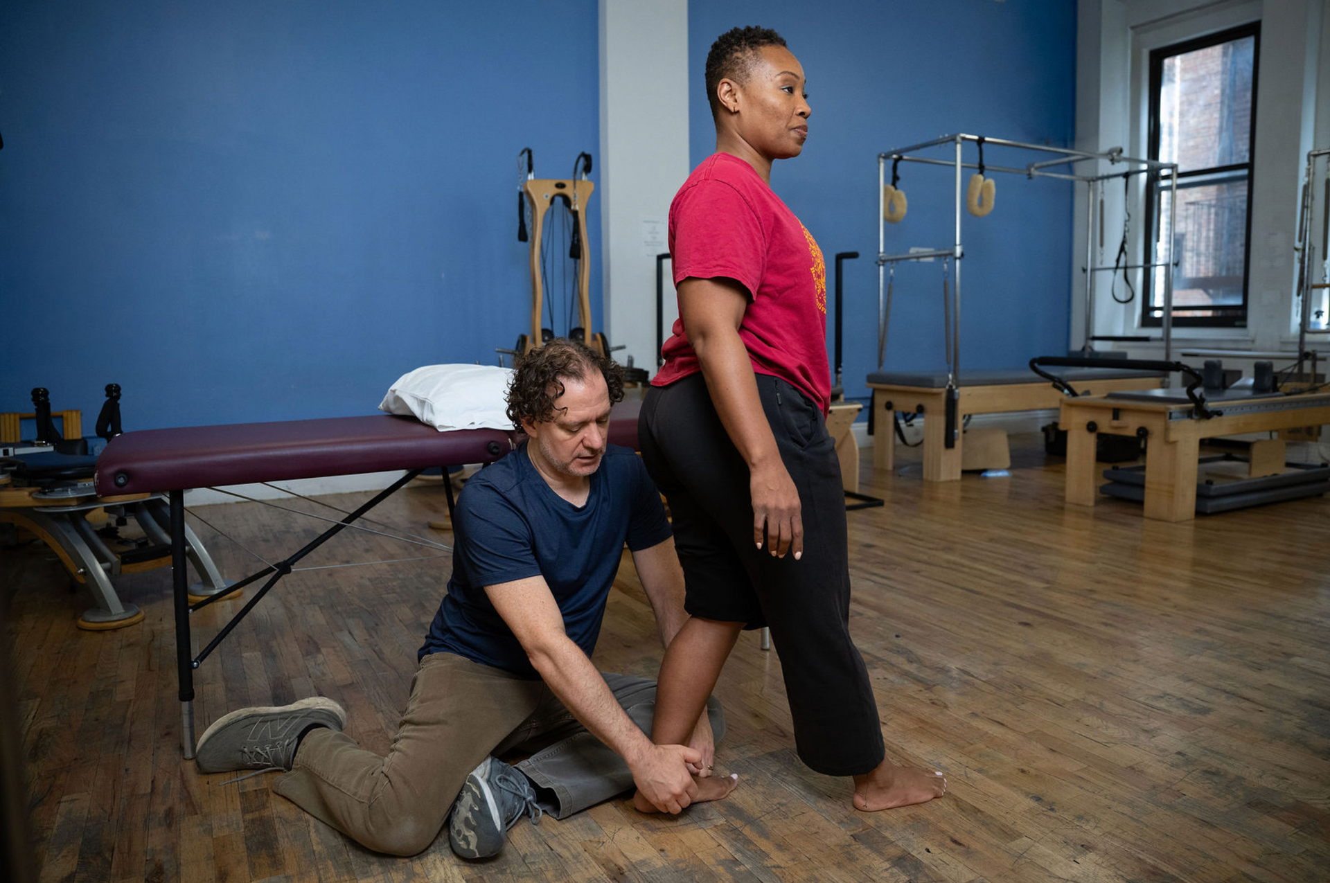 Person wrapping a black strap around an ankle on a gym mat
