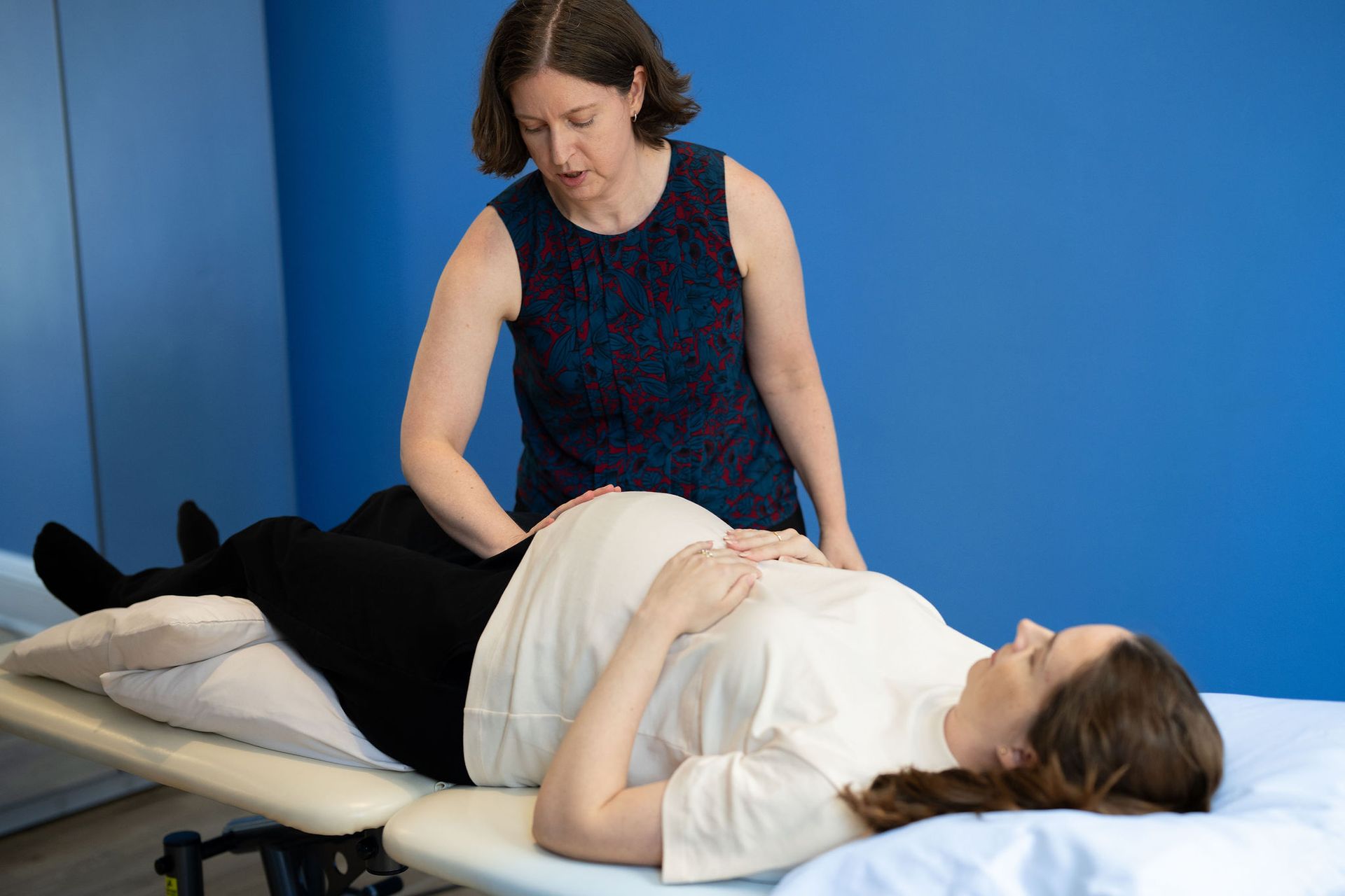 Physical therapist stretching a person’s pelvis while they lie on a treatment table