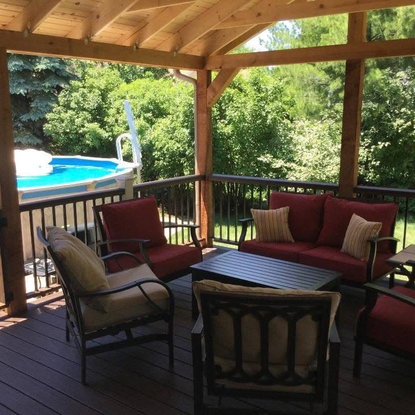 Covered porch with patio seating, overlooking a backyard pool and lush greenery.