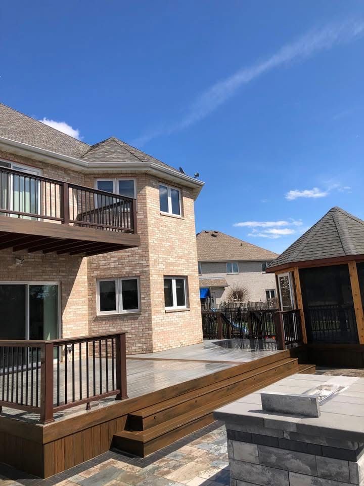 Backyard patio beside brick townhouses, with wooden deck, gazebo, and clear blue sky