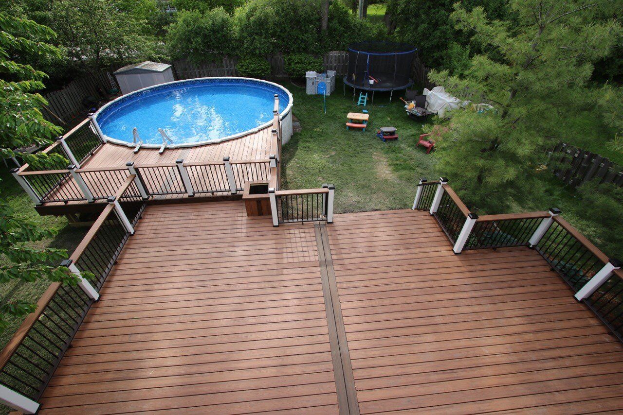 Wooden deck overlooking a blue above-ground pool and green backyard with patio furniture