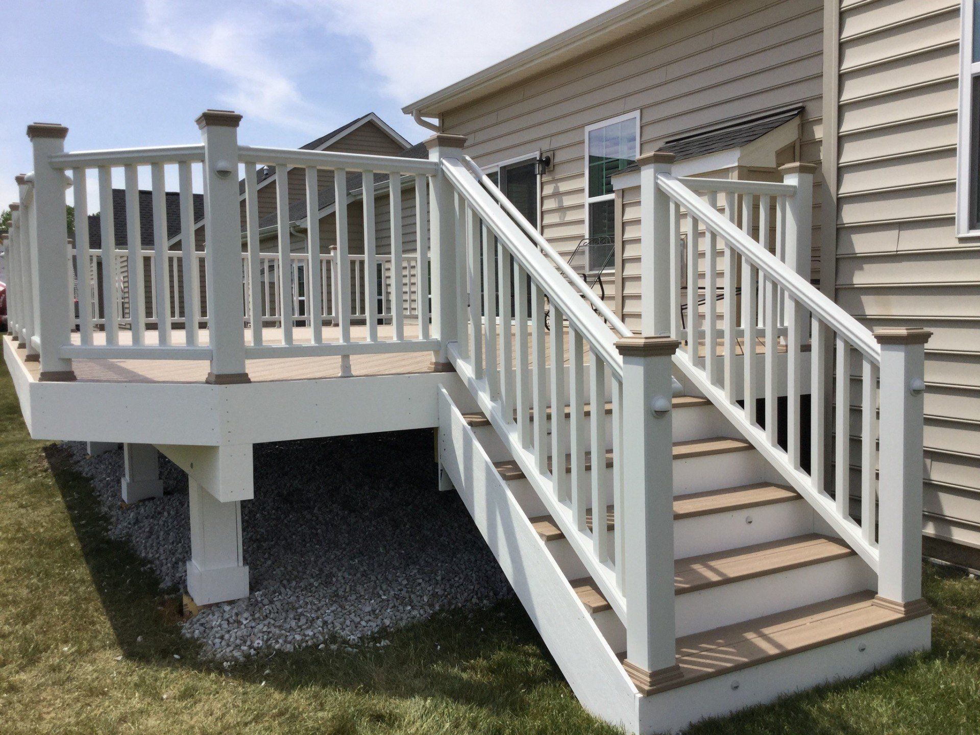 Raised wooden porch with white railings and stairs leading to a house entrance