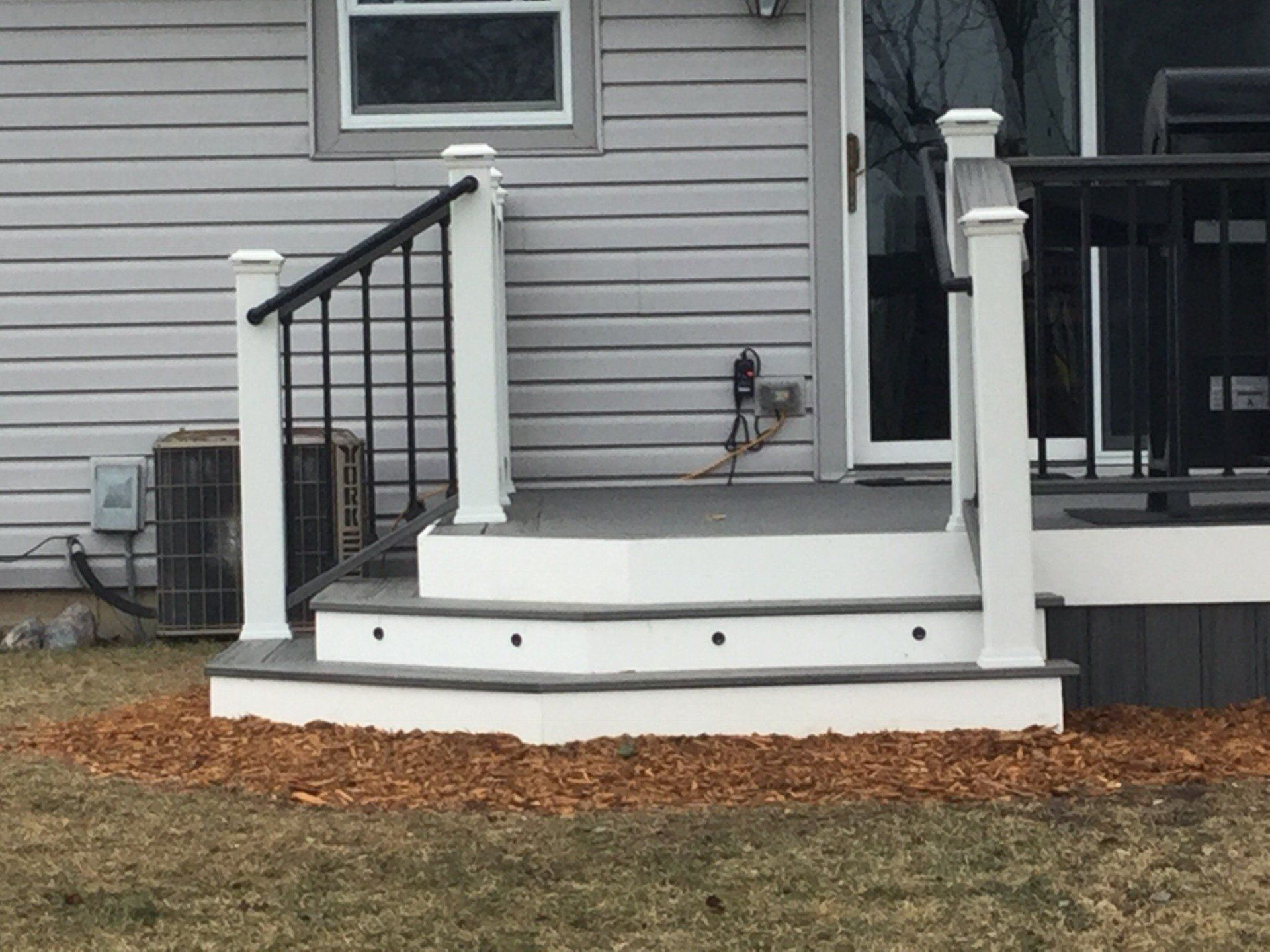 Front porch with white steps and black railings on a gray house