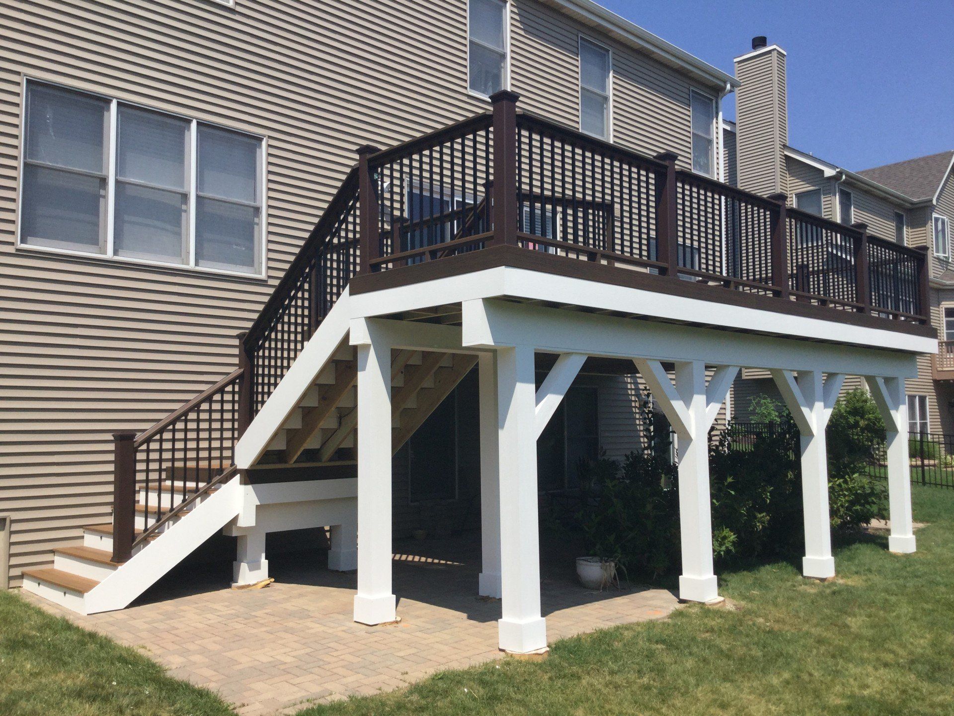 Back deck with dark railing and white support posts on the side of a house