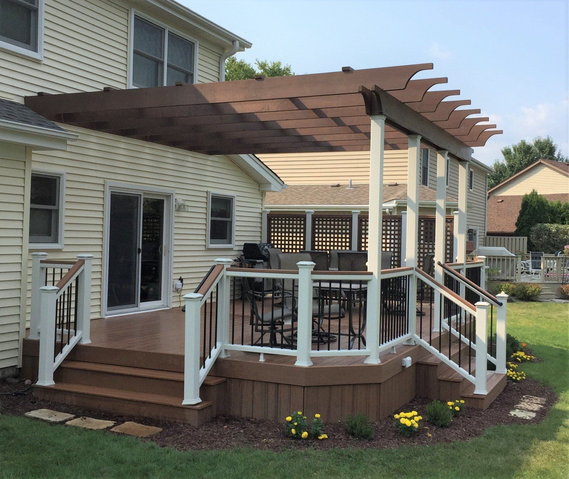 Backyard deck with pergola, railings, stairs, and outdoor seating beside a house