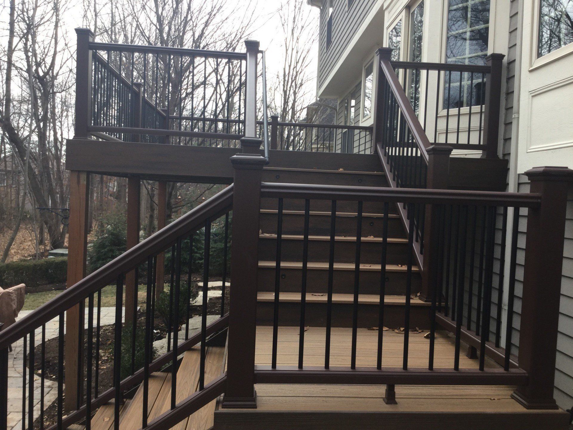 Front steps of a townhouse with metal railings and a small landing leading to a deck.