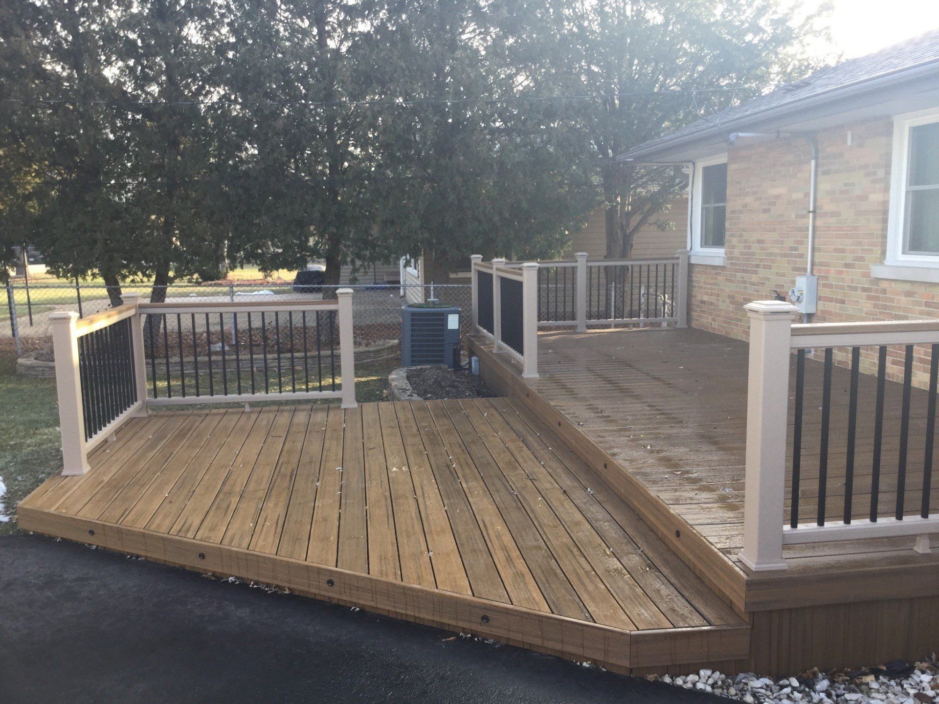 Wooden wheelchair ramp and deck beside a brick house, with railings and a small staircase.