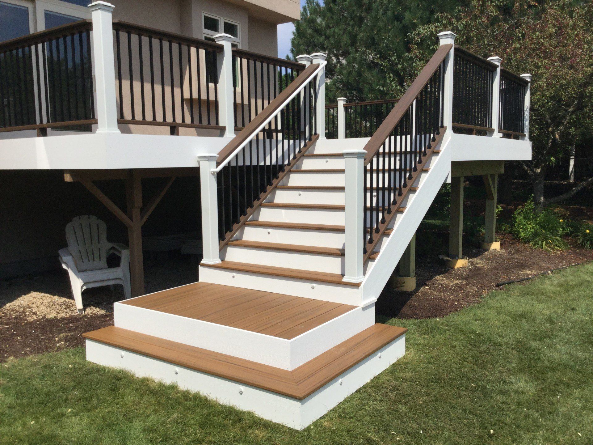 Backyard deck with white stairs leading to a raised wooden porch and small landing platform