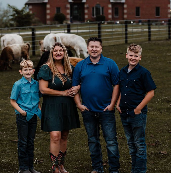 Family of 4 in standing in the mini highland cow pasture