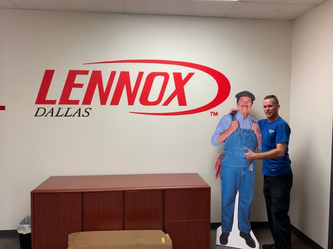Lennox Dallas wall logo with two people standing beside a wooden cabinet.