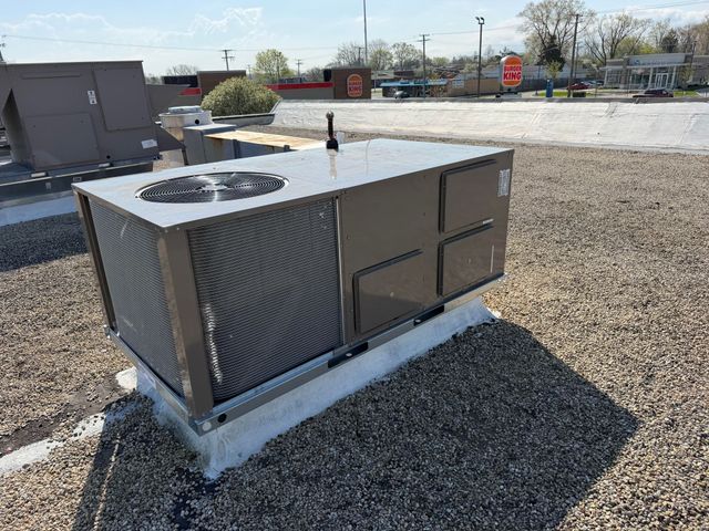 Gray rooftop HVAC unit on gravel with circular fan grilles and vent panels
