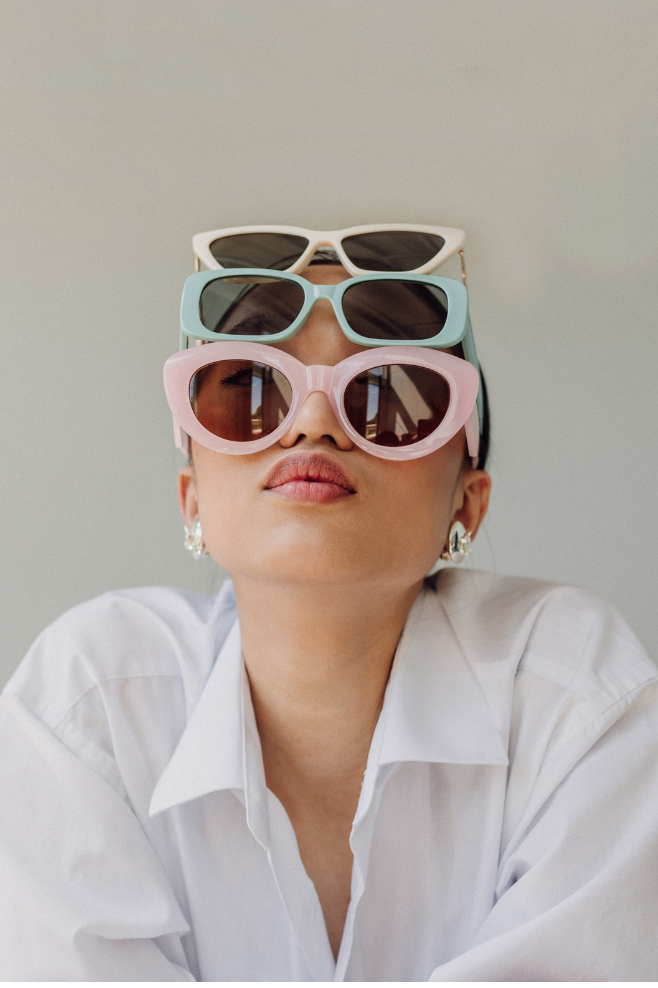 Una mujer que lleva una camisa blanca y gafas de sol apiladas una encima de la otra.