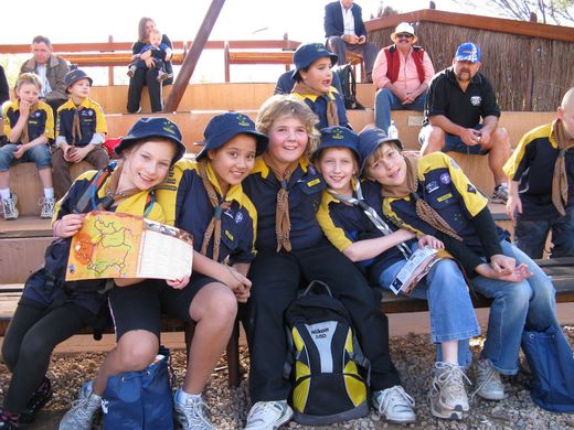 Group of scouts, wearing uniforms, posing with a map outdoors.