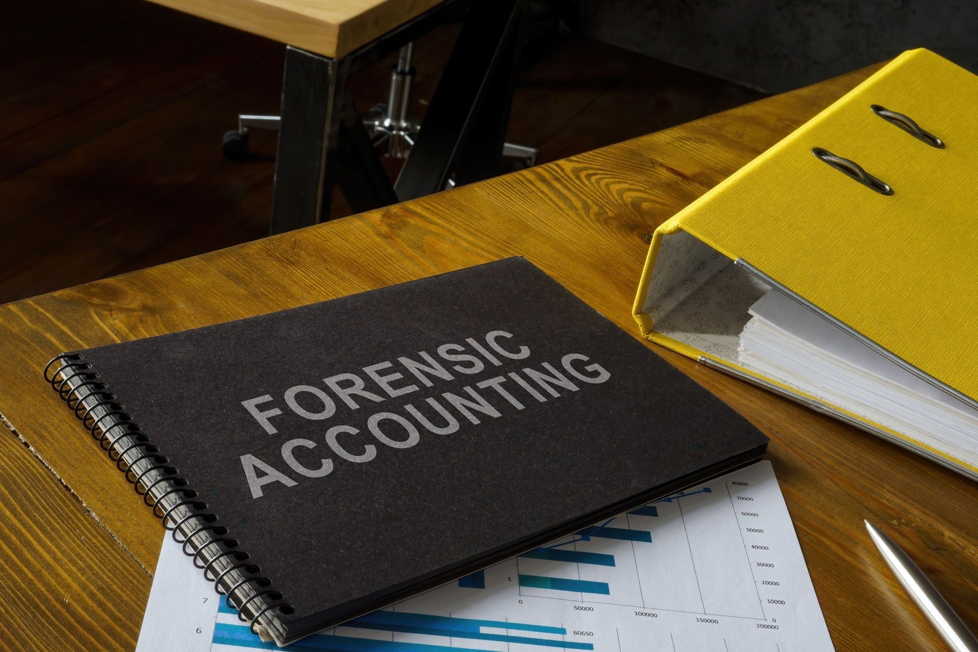 A book titled forensic accounting is sitting on a wooden table.