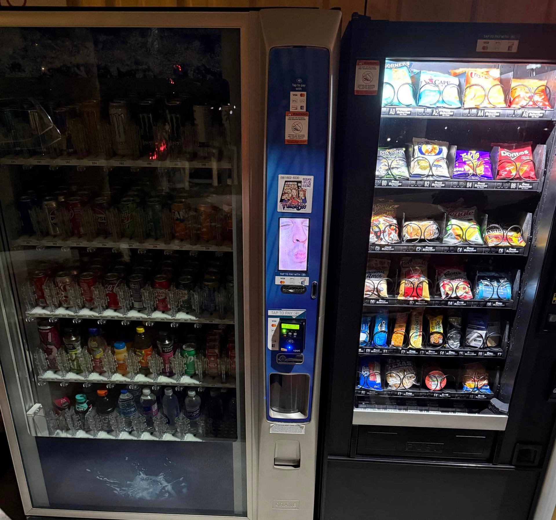 Two vending machines side-by-side, one filled with beverages and the other with snacks, separated by a central kiosk.